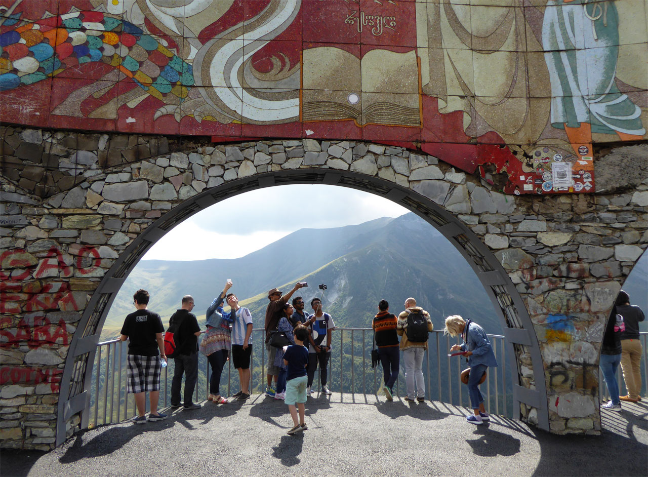 Tourists with selfie sticks at the Russia-Georgia Friendship Monument