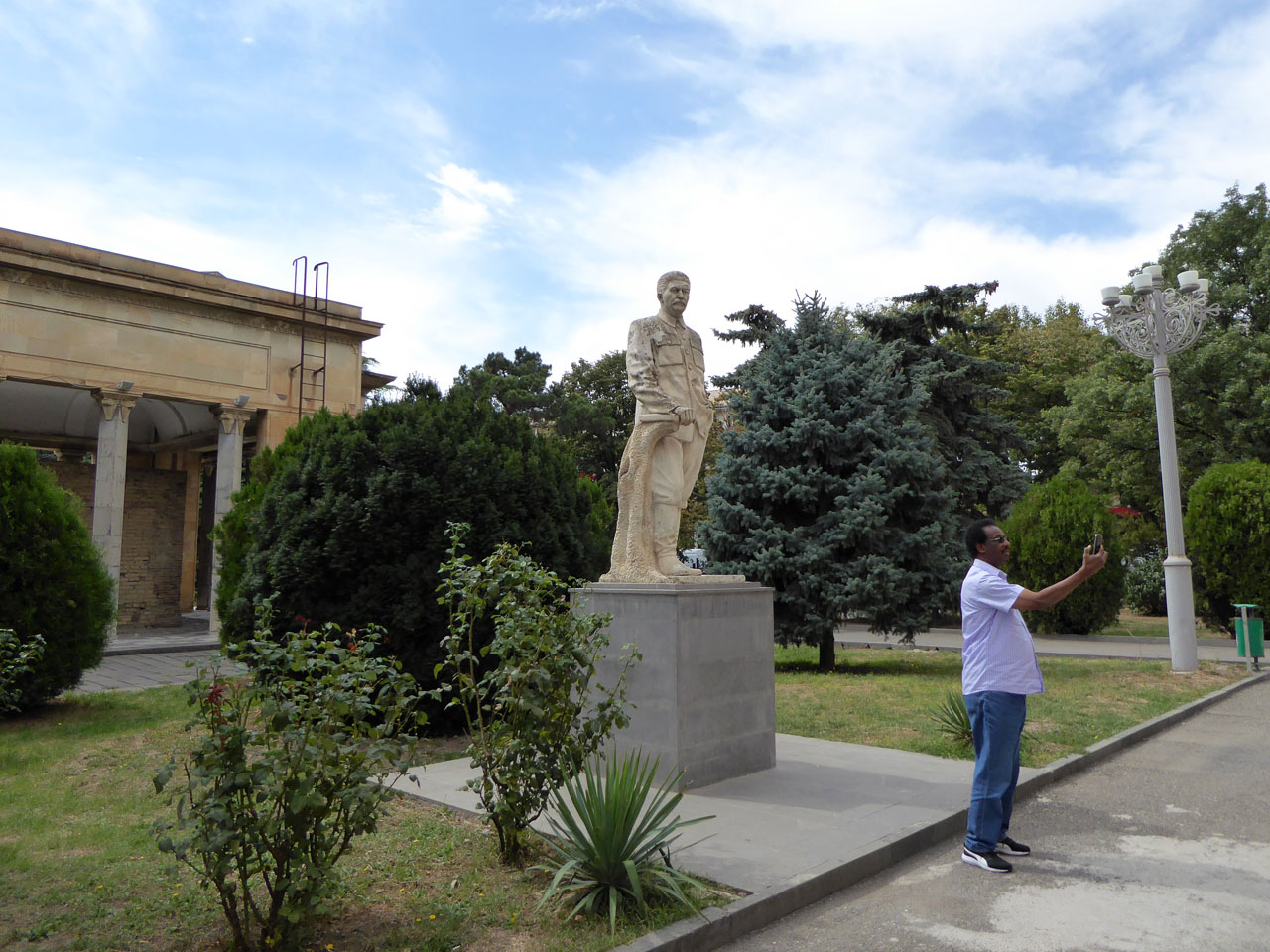 Man taking a selfie in front of Stalin statue in Gori, Georgia